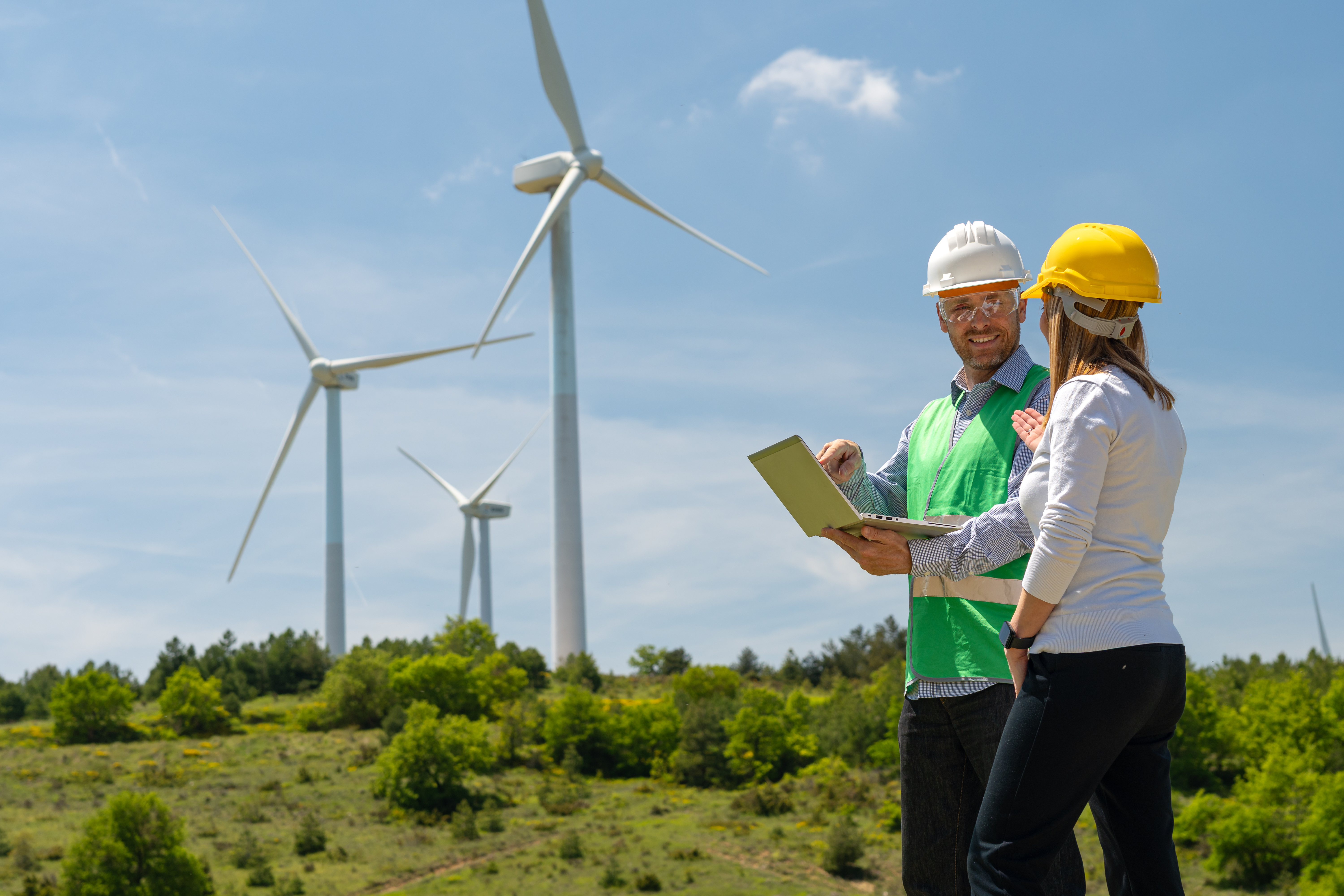 A male and female engineer talking in front of wind turbines